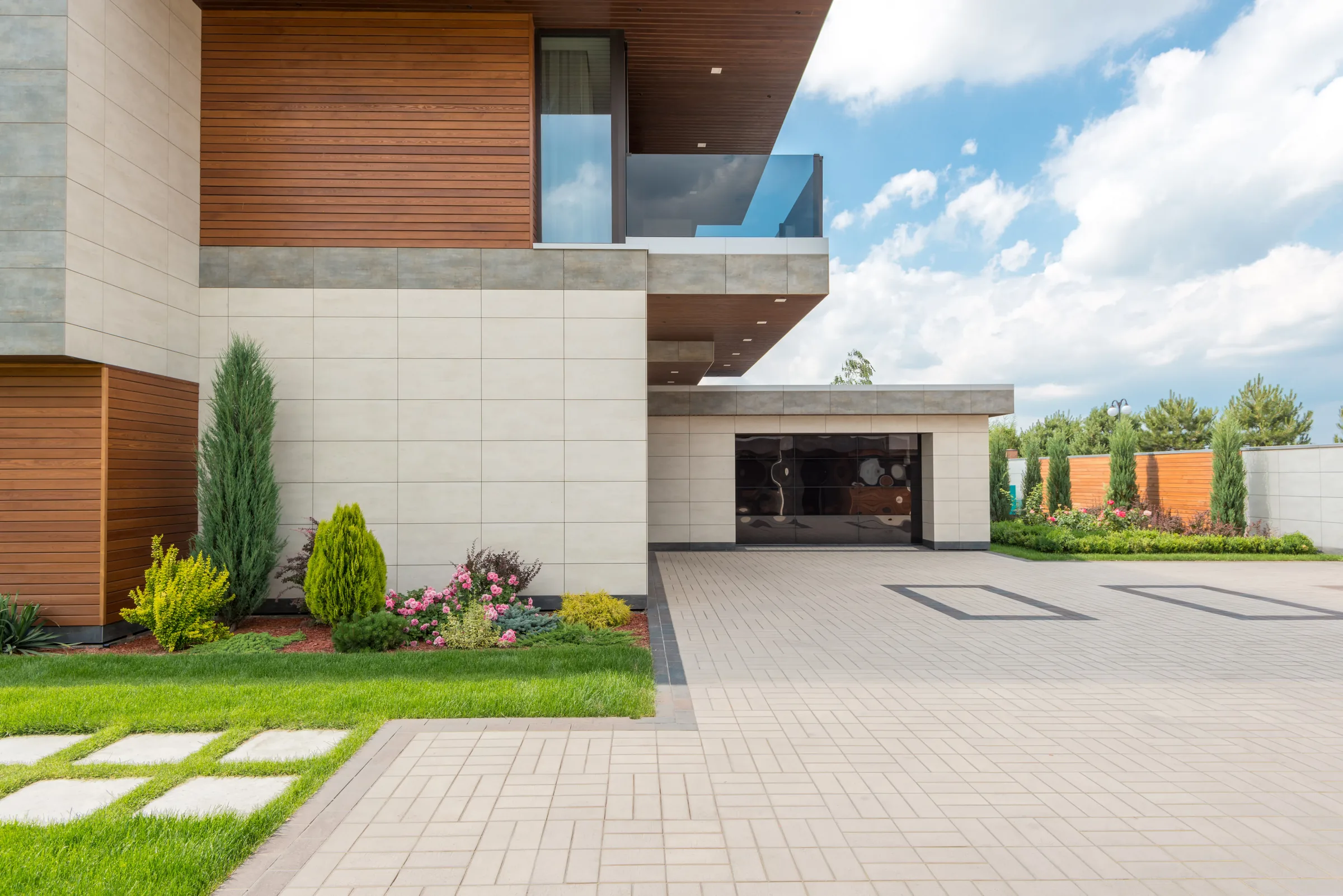 Modern home exterior with large windows, wood accents, and landscaped front yard.